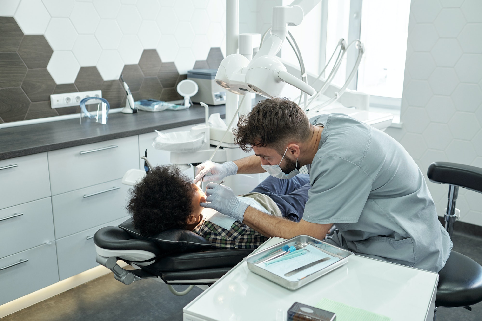 Contemporary dentist bending over little patient