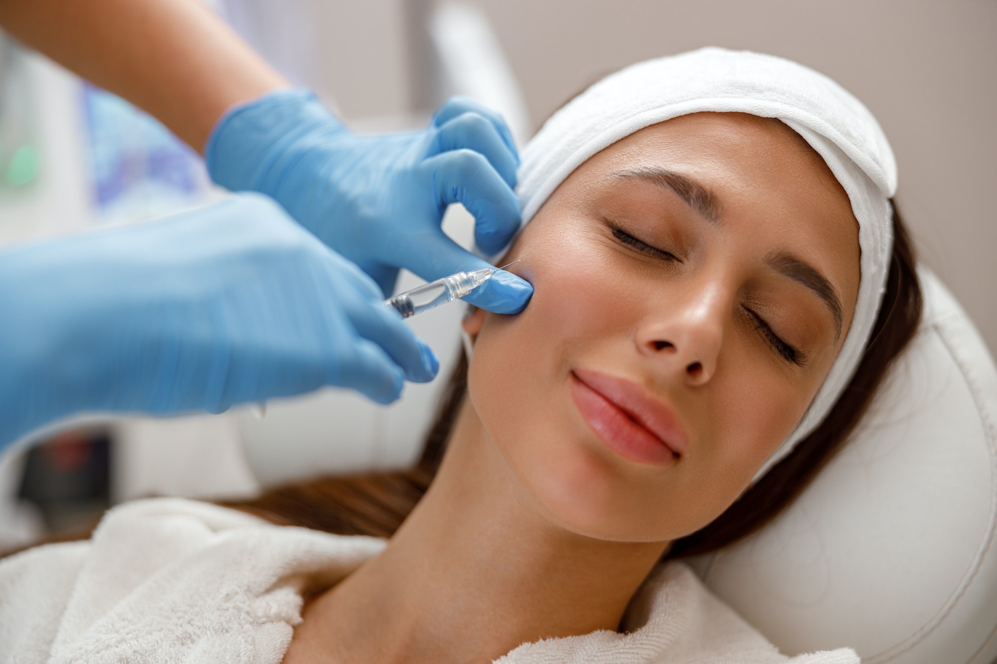 Woman getting injection in her face at plastic surgery clinic